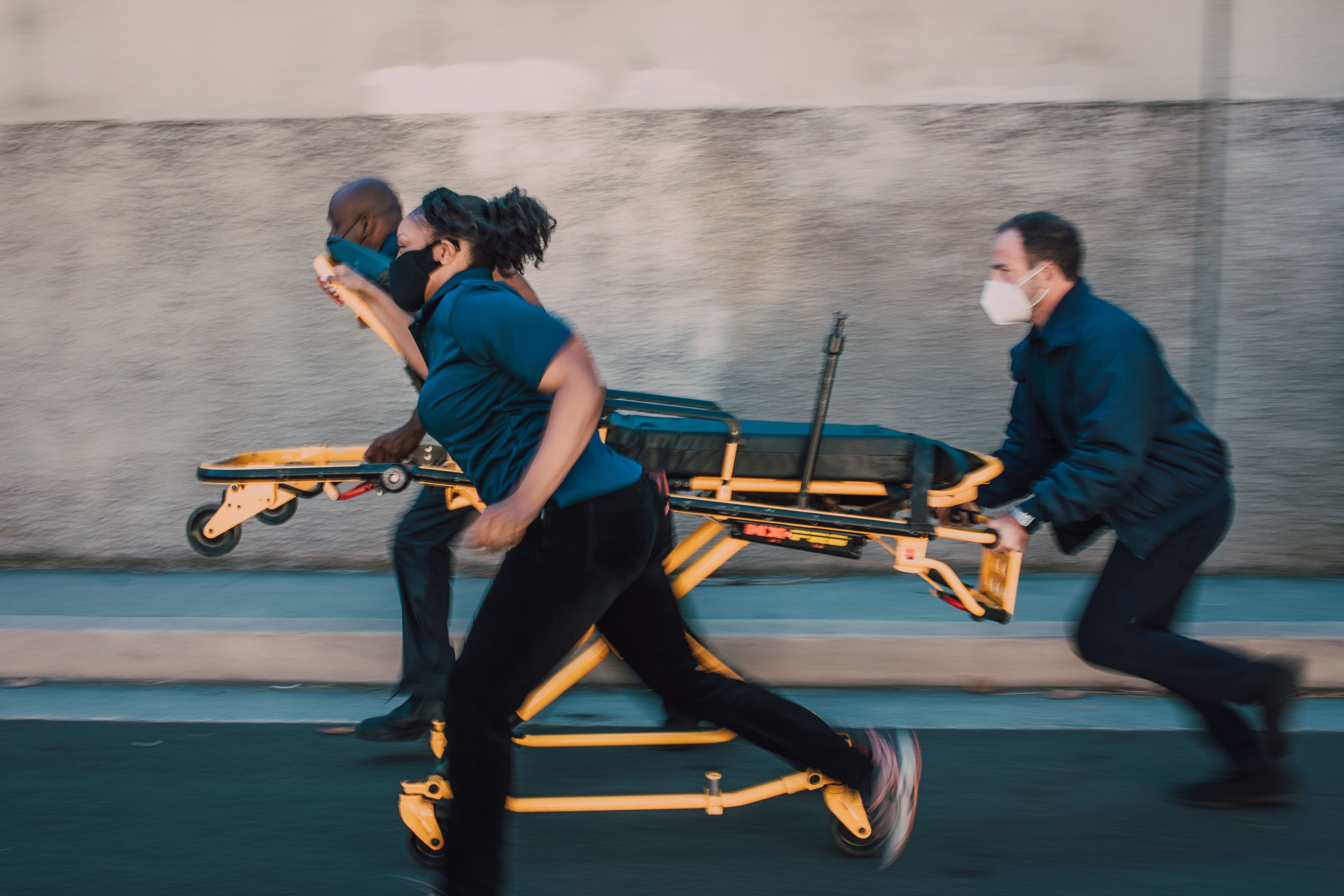 Dynamic shot of paramedics running with a stretcher on a street, showcasing urgency and teamwork.